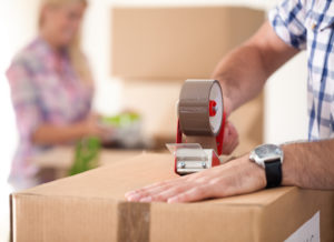 Close up of male hand packing cardboard box, concept moving house